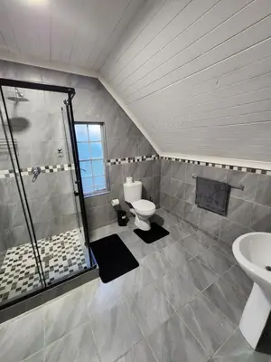a bathroom with a shower and a toilet and a sink at Bush Babies Cottage in Marloth Park