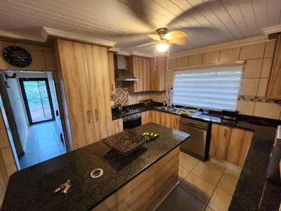 a kitchen with wooden cabinets and a black counter top at Bush Babies Cottage in Marloth Park