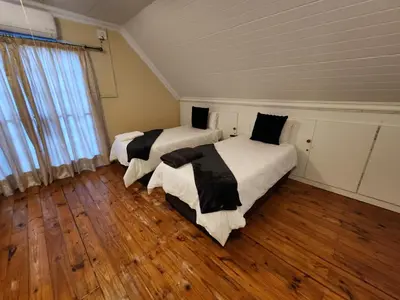 two beds in a room with wooden floors at Bush Babies Cottage in Marloth Park