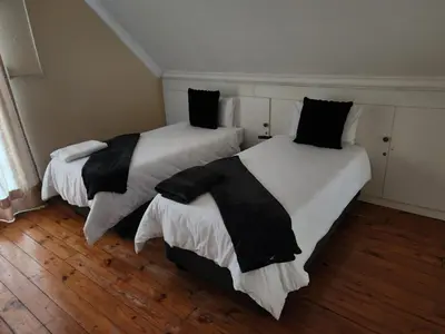 two beds with black and white sheets in a room at Bush Babies Cottage in Marloth Park