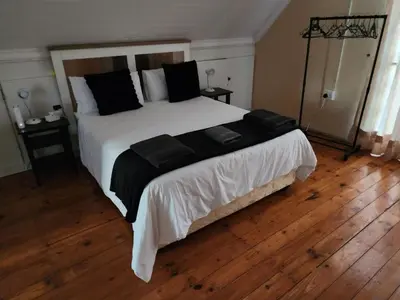 a bedroom with a large white bed with black pillows at Bush Babies Cottage in Marloth Park