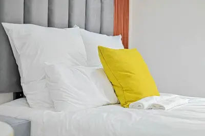 a bed with white pillows and a yellow pillow at Sunset Lodge - Gundani in Thengwe