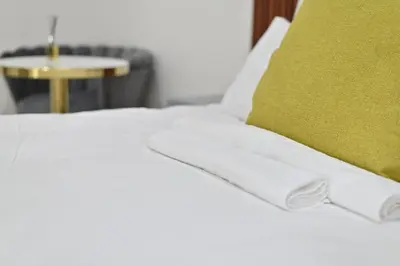 a white bed with a green pillow and a table at Sunset Lodge - Gundani in Thengwe