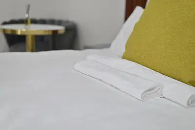 a bed with white sheets and a green pillow at Sunset Lodge - Gundani in Thengwe