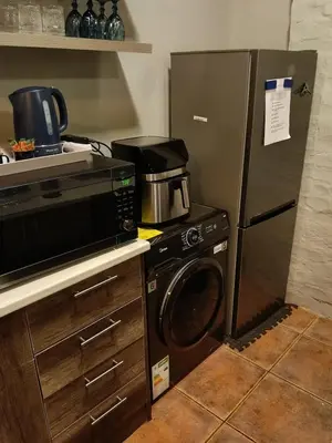 a kitchen with a microwave and a refrigerator at Cozy Corner Cottage near wilgers hospital & Menlyn in Pretoria