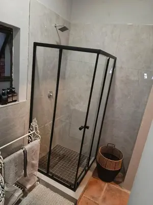 a shower with a glass door in a bathroom at Cozy Corner Cottage near wilgers hospital & Menlyn in Pretoria