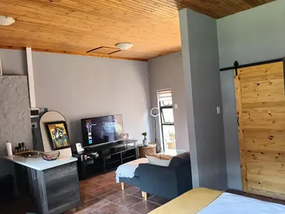 a living room with a couch and a tv at Cozy Corner Cottage near wilgers hospital & Menlyn in Pretoria