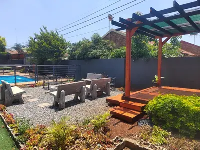a patio with benches and a wooden pergola at Palma Spaces in Pretoria