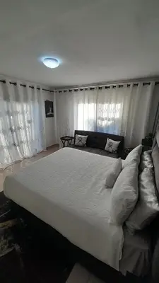 a large white bed in a bedroom with curtains at Palma Spaces in Pretoria