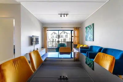 a living room with blue and orange chairs at #AlimamaSpaces The Rob's Munyaka in Midrand