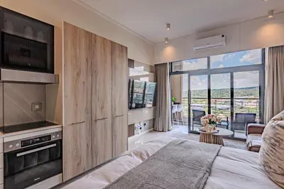 a bedroom with a bed and a view of a balcony at 1606 Menlyn Maine Residence Luxury Apartments in Pretoria