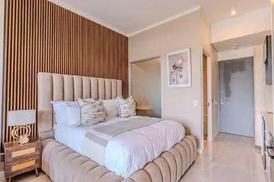 a bedroom with a large bed with a large headboard at 1606 Menlyn Maine Residence Luxury Apartments in Pretoria