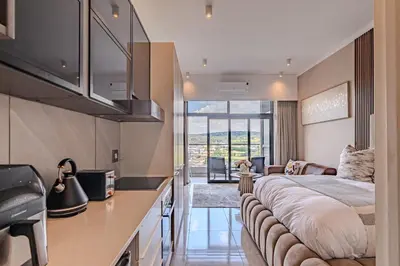 a bedroom with a large bed and a living room at 1606 Menlyn Maine Residence Luxury Apartments in Pretoria