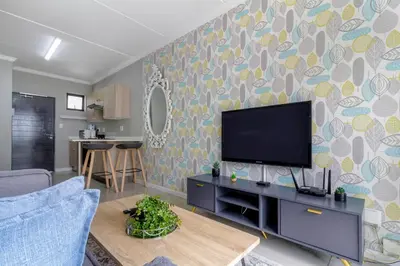 a living room with a flat screen tv on a wall at #AlimamaSpaces The Manson's Heights in Midrand