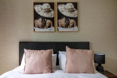 a bedroom with two pictures on the wall above a bed at #AlimamaSpaces The Manson's Heights in Midrand