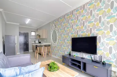 a living room with a flat screen tv on a wall at #AlimamaSpaces The Manson's Heights in Midrand