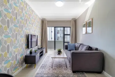 a living room with a couch and a tv at #AlimamaSpaces The Manson's Heights in Midrand