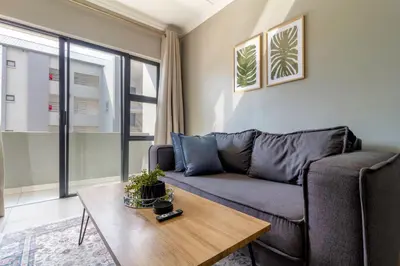 a living room with a couch and a table at #AlimamaSpaces The Manson's Heights in Midrand