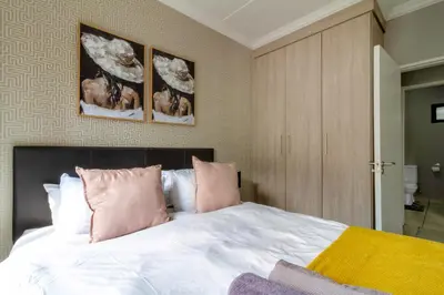 a bedroom with a large white bed with pink pillows at #AlimamaSpaces The Manson's Heights in Midrand