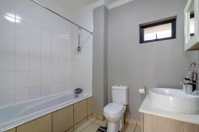 a bathroom with a tub and a toilet and a sink at #AlimamaSpaces The Manson's Heights in Midrand