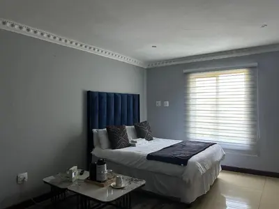 a bedroom with a bed and a table and a window at Homely Palace in Midrand