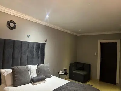 a bedroom with a bed and a chair at Homely Palace in Midrand