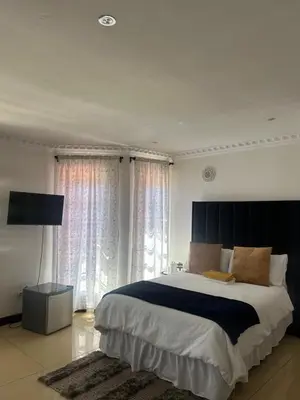 a bedroom with a large bed and a large window at Homely Palace in Midrand