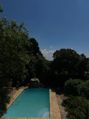a blue swimming pool with trees in the background at Homely Palace in Midrand