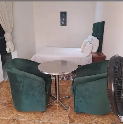 a room with a table and a couch and a bed at Aquamarine Guesthouse in Mabopane