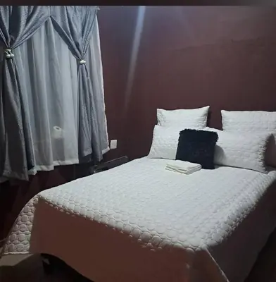 a white bed with a book on top of it at Aquamarine Guesthouse in Mabopane