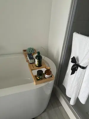 a bathroom with a bathtub with a wooden tray on the side at Stylish Dante Trilogy Menlyn Maine Apartment in Pretoria
