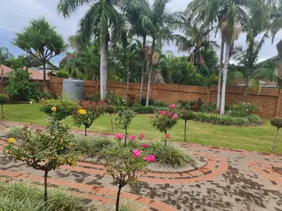 a garden with flowers and trees and a brick wall at A Pearl Place in Pretoria