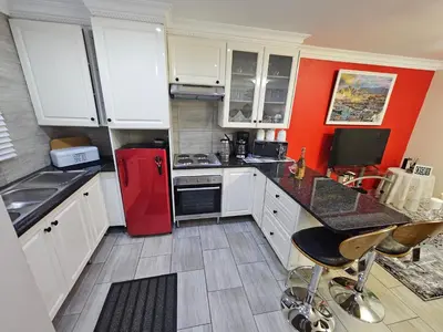 a kitchen with white cabinets and a red refrigerator at A Pearl Place in Pretoria