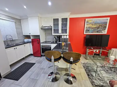 a kitchen with a red wall and two stools at A Pearl Place in Pretoria