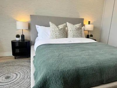 a bedroom with a bed with a green blanket and pillows at Ellipse Waterfall in Midrand