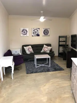 a living room with a couch and a table at Studio at 26 in Centurion