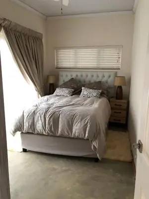 a bedroom with a large bed and a window at Studio at 26 in Centurion