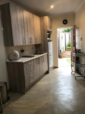 a kitchen with wooden cabinets and a door to a yard at Studio at 26 in Centurion