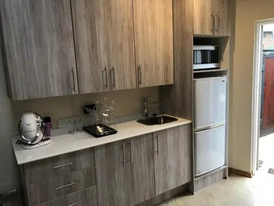 a kitchen with wooden cabinets and a sink and a refrigerator at Studio at 26 in Centurion