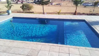 a swimming pool with blue water in a yard at JandJ Guest House in Armburg
