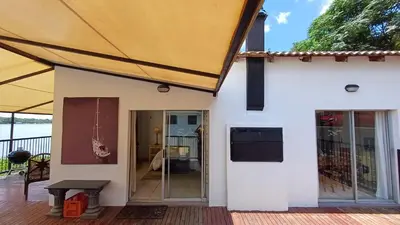 a white house with a large tent on a deck at Boathouse 203 in Hartbeespoort