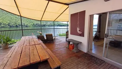a deck with a wooden table and a view of the water at Boathouse 203 in Hartbeespoort