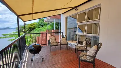 a porch with chairs and a table and a view of the water at Boathouse 203 in Hartbeespoort