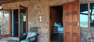 an open door of a stone house with a bedroom at Vaalkop Dam Reserve, self-catering log cabin holiday home in Beestekraal, South Africa in Beestekraal