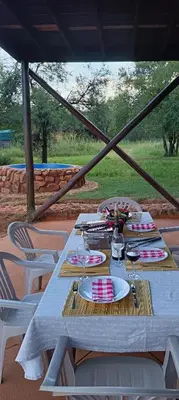 a table with plates and wine glasses on it at Vaalkop Dam Reserve, self-catering log cabin holiday home in Beestekraal, South Africa in Beestekraal