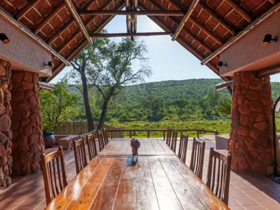 a dog sitting at a wooden table on a patio at Thaba Metsi Private Game Lodge - Welgevonden in Vaalwater