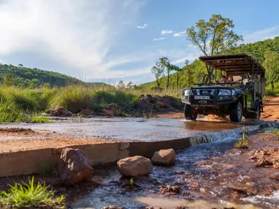 a jeep driving through a stream in a river at Thaba Metsi Private Game Lodge - Welgevonden in Vaalwater