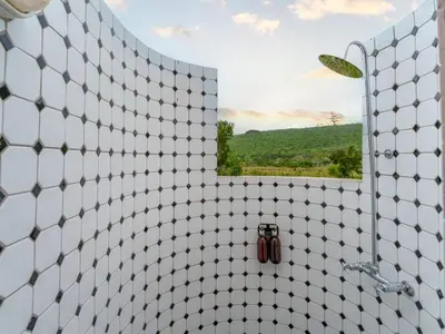 a bathroom with a white tiled shower with a mirror at Thaba Metsi Private Game Lodge - Welgevonden in Vaalwater