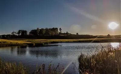 a body of water with the sun in the background at LINGER LONGER COUNTRY RETREAT, Dullstroom in Dullstroom
