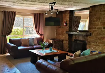 a living room with leather furniture and a fireplace at LINGER LONGER COUNTRY RETREAT, Dullstroom in Dullstroom